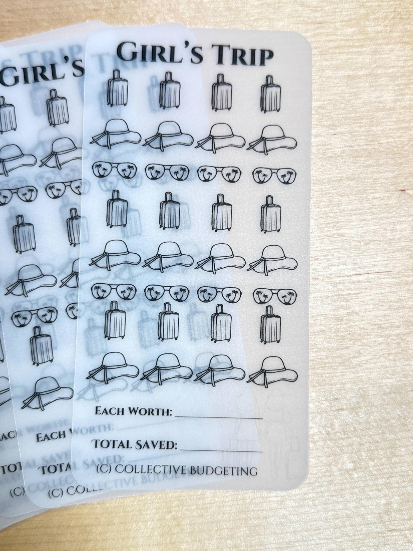 Two transparent sheets with a black and white design of suitcases, sunglasses, and sun hats. The sheets have the text 'Girl's Trip' at the top and the text 'Each Worth:', 'Total Saved:', and '(C) Collective Budgeting' at the bottom.