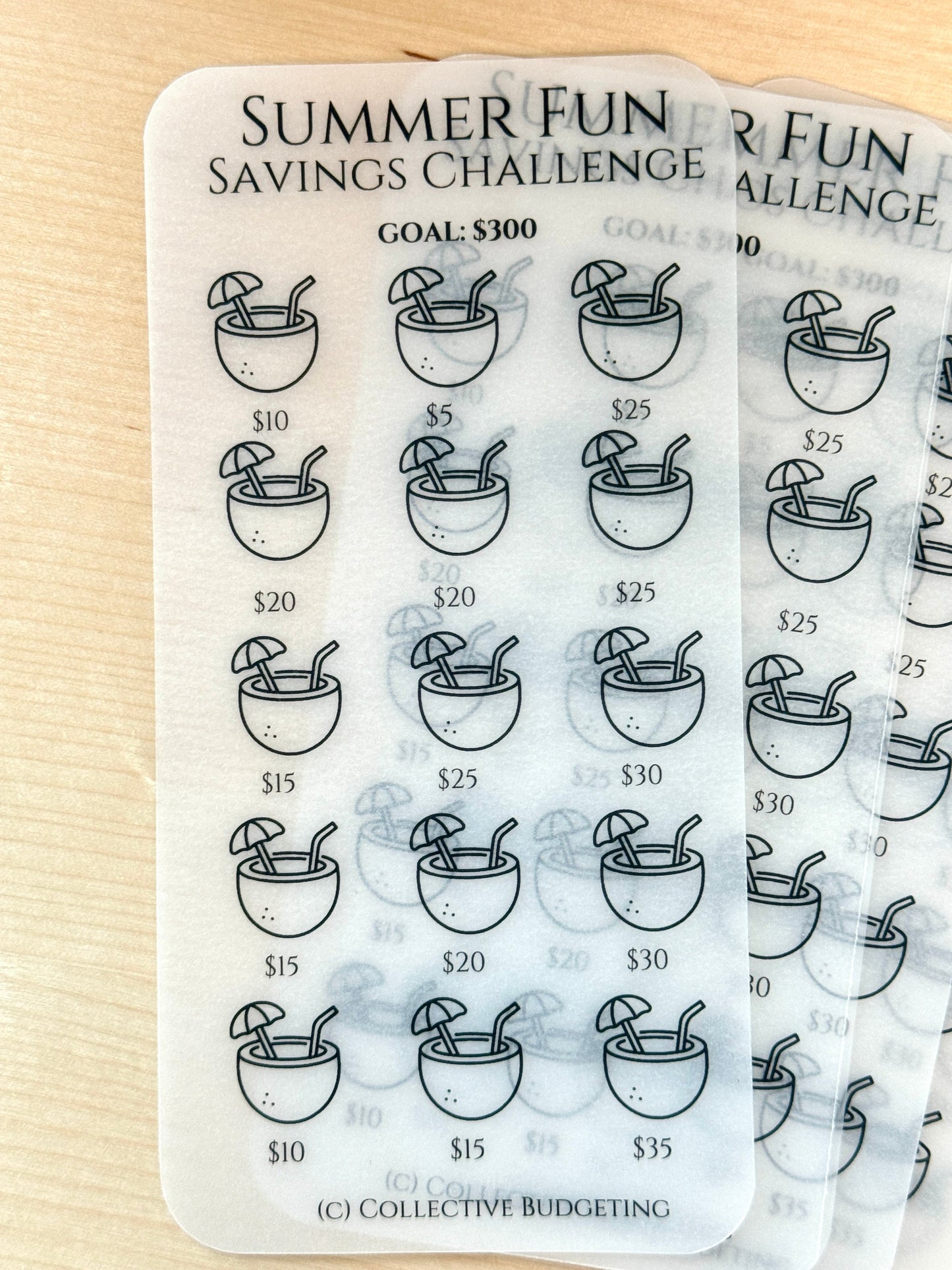 A white sheet of paper with a black and white design of a coconut with an umbrella and two straws. The sheet has the text 'Summer Fun Savings Challenge' and 'Goal: $300' printed on it. The sheet is divided into a grid of 12 squares, each containing a coconut with an umbrella and two straws. The coconuts are labeled with dollar amounts, ranging from $5 to $35. The sheet also has the text '(C) Collective Budgeting' printed on it.