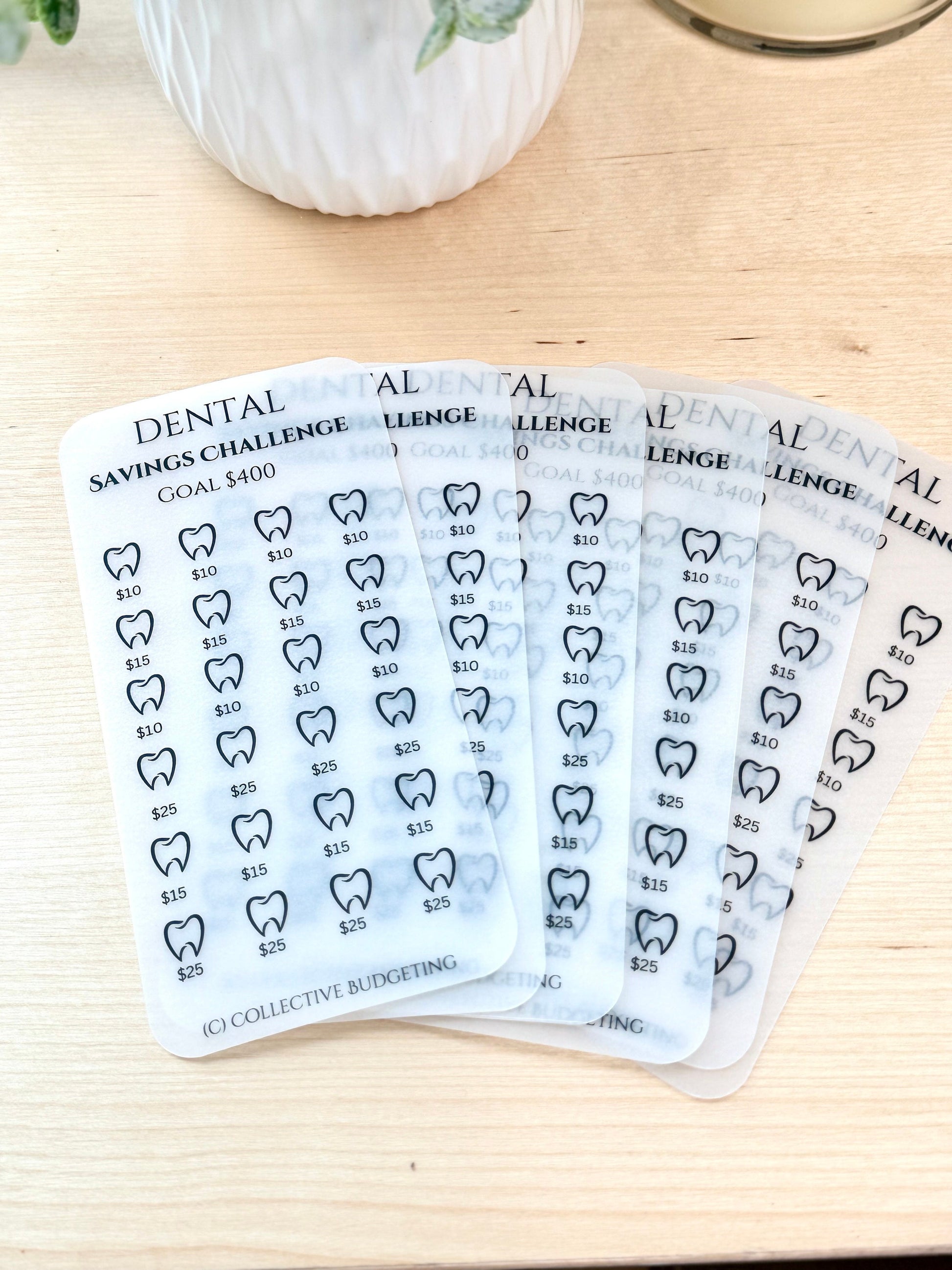 Six transparent sheets with a dental savings challenge theme. Each sheet has a goal of $400 and features a grid of teeth with dollar amounts of $10, $15, and $25. The text (C) COLLECTIVE BUDGETING is at the bottom of the sheet.