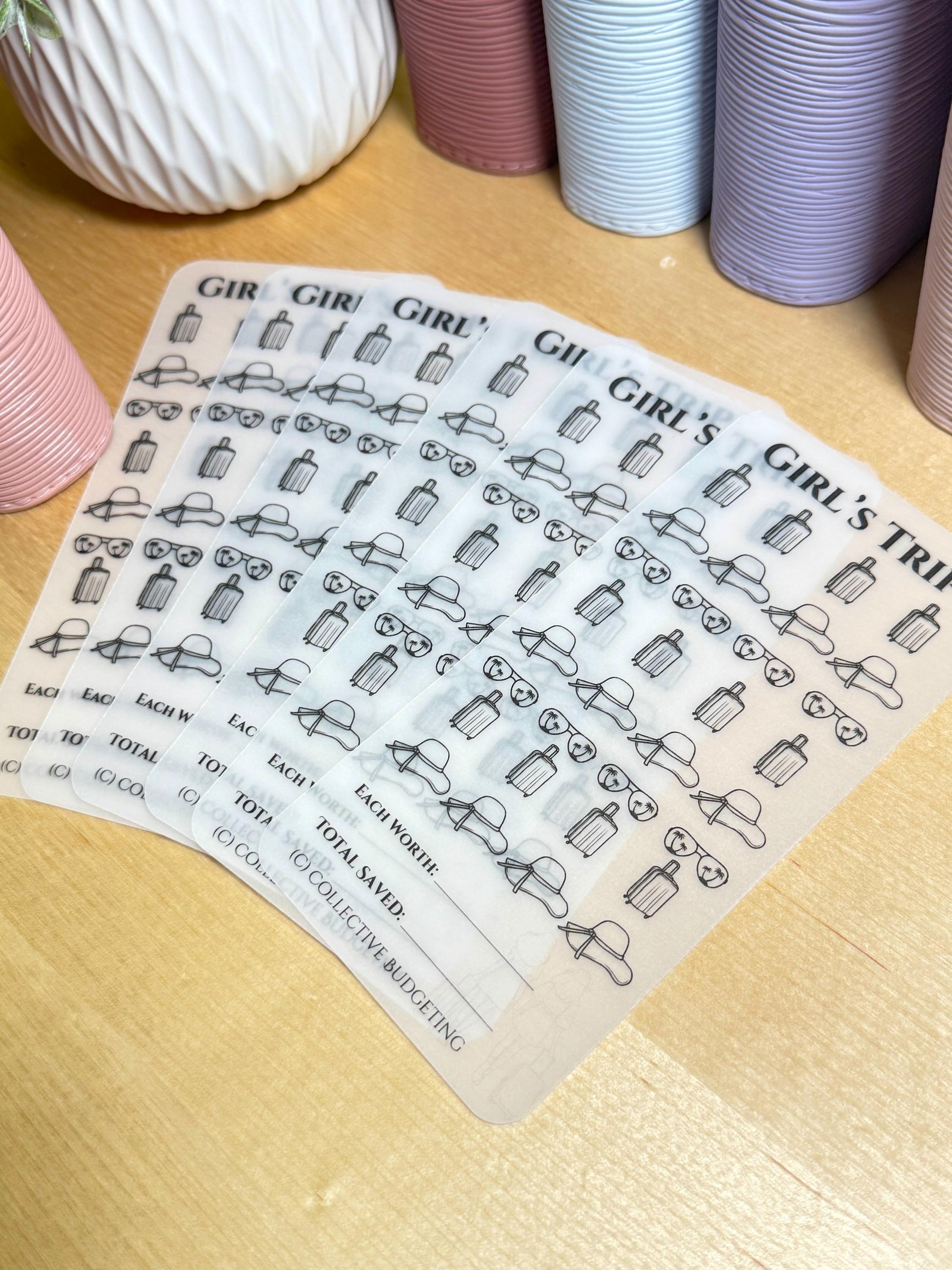 Six clear sheets of stickers with black outlines of suitcases, sunglasses, and sun hats. The stickers are labeled 'Girl's Trip' and have a section for 'Each Worth', 'Total Saved', and '(C) Collective Budgeting'.