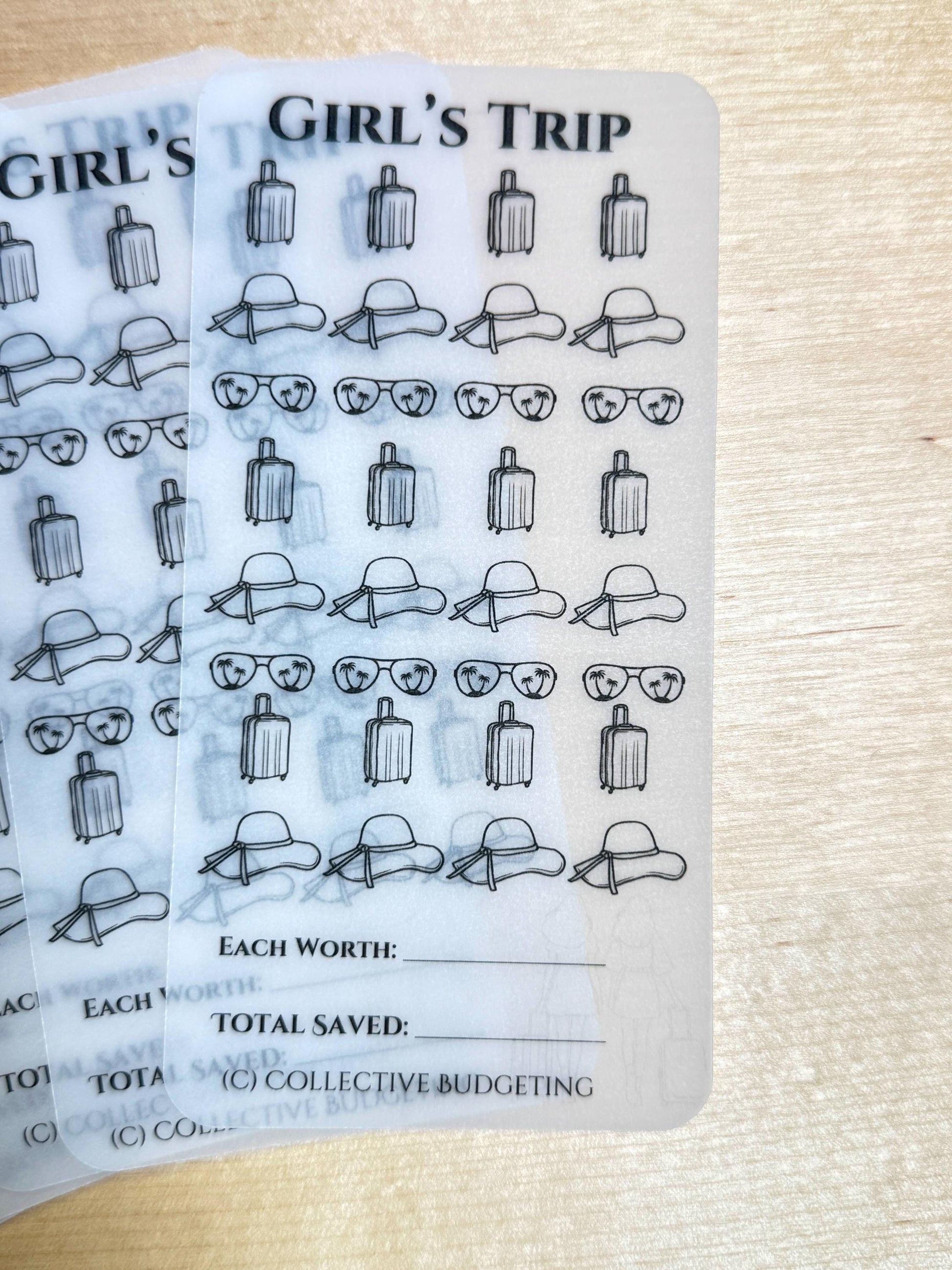 Two transparent sheets with a black and white design of suitcases, sunglasses, and sun hats. The sheets have the text 'Girl's Trip' at the top and the text 'Each Worth:', 'Total Saved:', and '(C) Collective Budgeting' at the bottom.