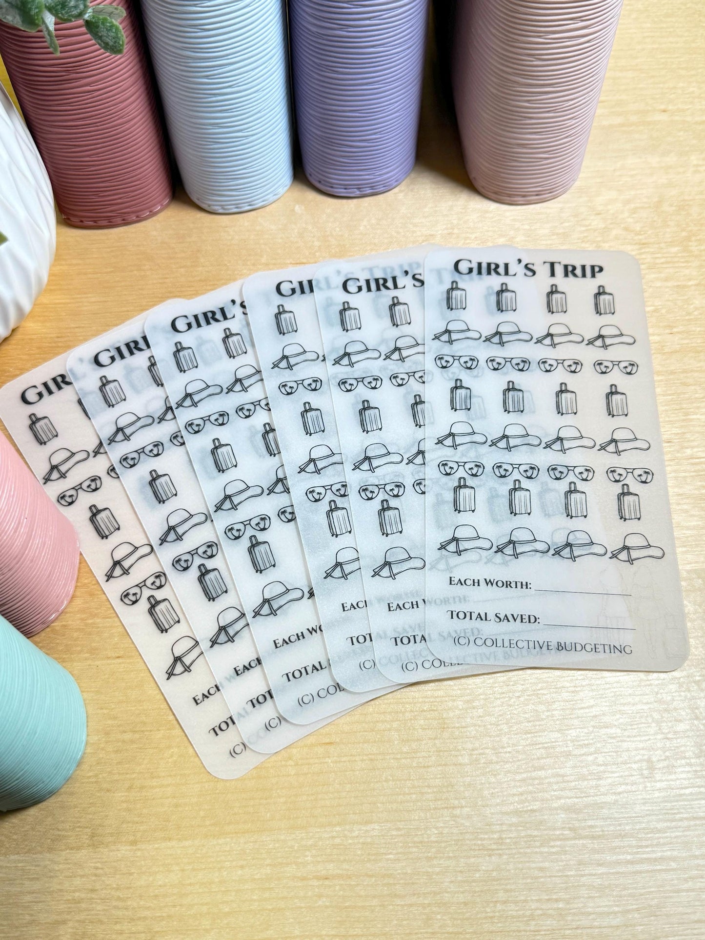 Five transparent sheets with black outlines of suitcases, sunglasses, and sun hats. The sheets are labeled 'Girl's Trip' and have a section for 'Each Worth', 'Total Saved', and 'Collective Budgeting'.