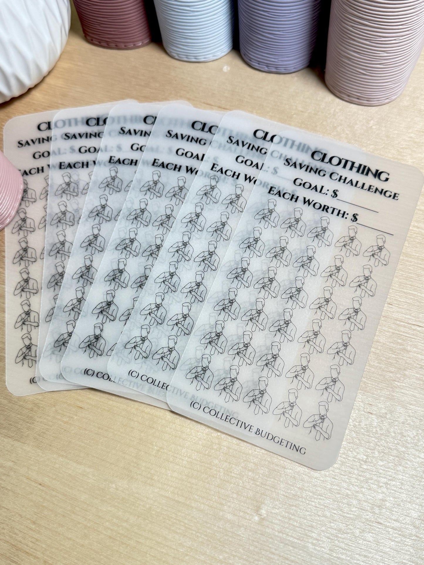 Five transparent sheets with black outlines of a person with their arms crossed. The sheets are stacked on top of each other. The top sheet has the text 'Clothing Saving Challenge' and 'Goal: $ Each Worth: $.' The bottom sheet has the text '(C) Collective Budgeting'.