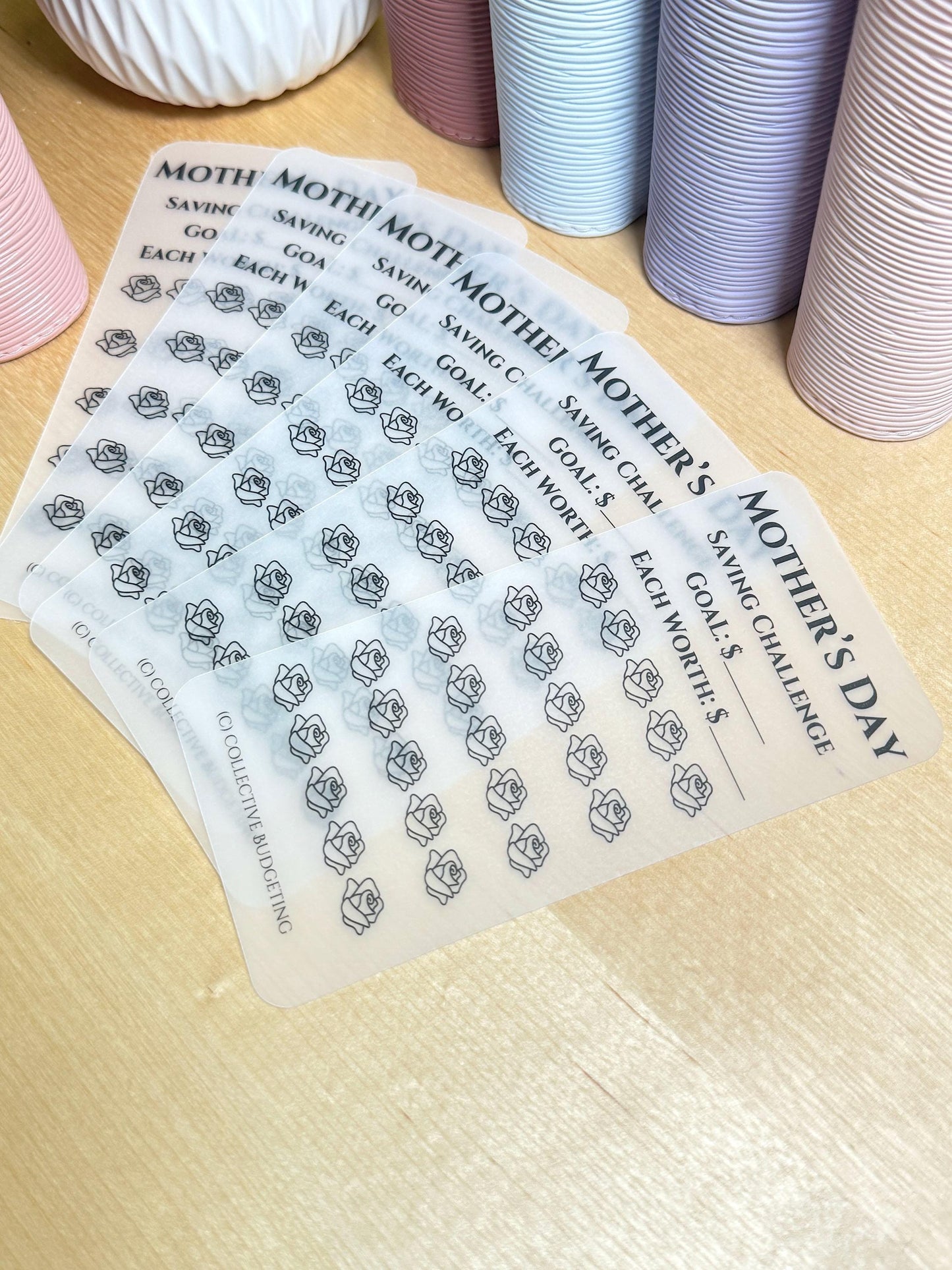 Six clear sheets with black text and rose outlines. The text reads 'Mother's Day Saving Challenge Goal: $ Each Worth: $ (c) Collective Budgeting'.