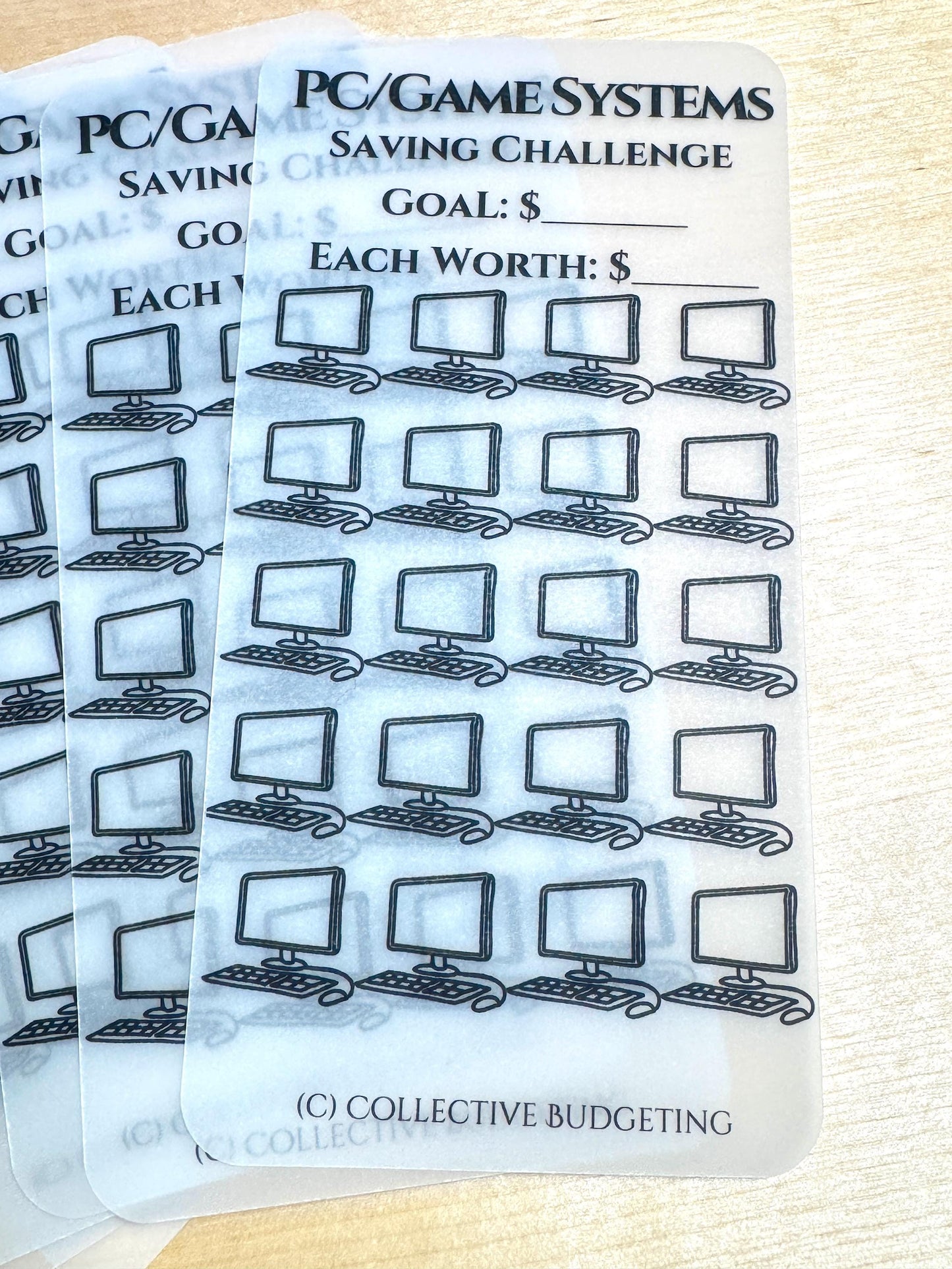 A white, translucent sheet with a black and white computer icon repeated 36 times. The sheet has the text 'PC/GAME SYSTEMS SAVING CHALLENGE' at the top. There are two blank lines below the text for writing in the goal amount and the amount each icon is worth. The text '(C) COLLECTIVE BUDGETING' is at the bottom of the sheet.