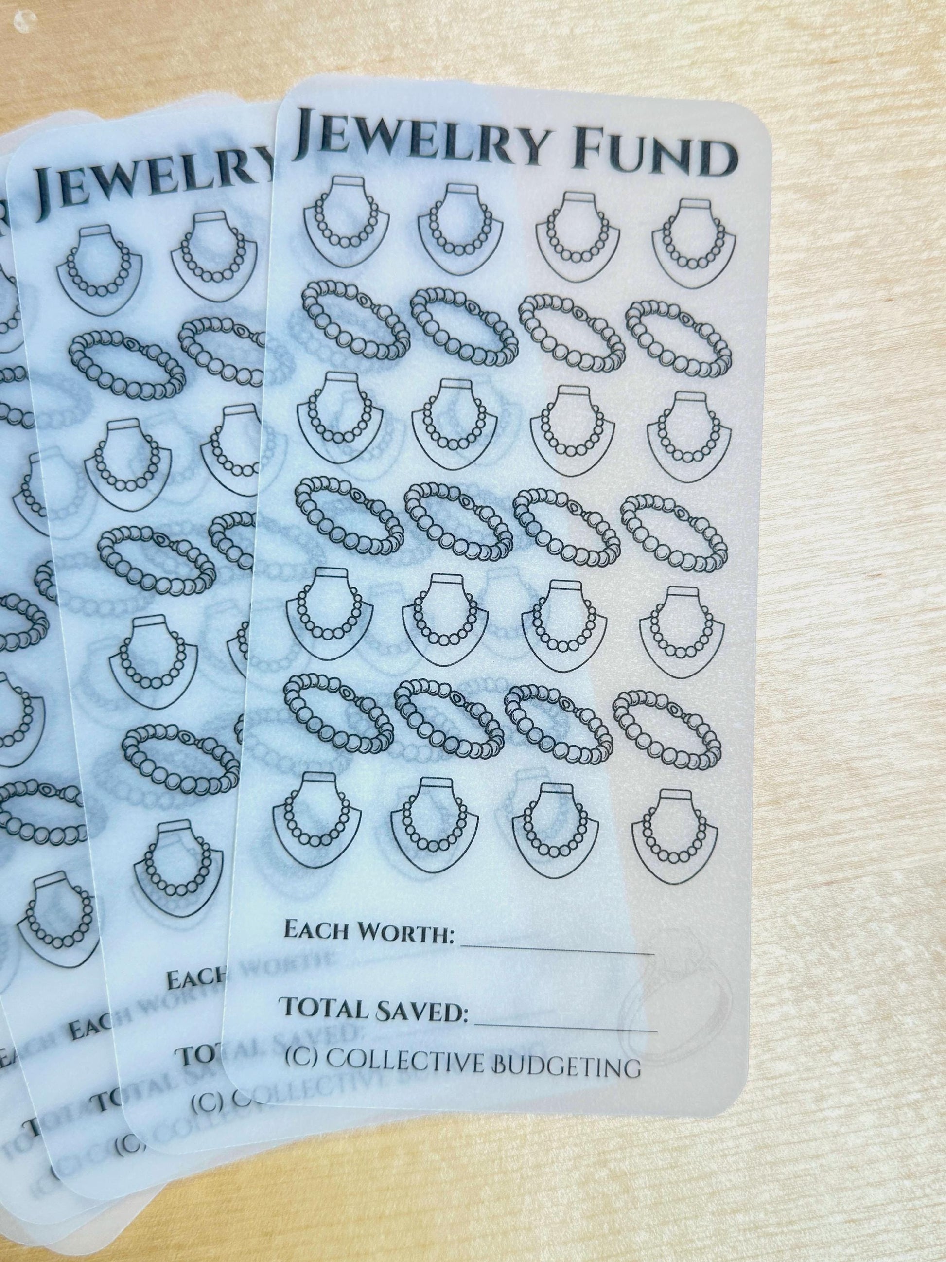 transparent sheets with a black and white design of necklaces. The sheets have the text 'JEWELRY FUND', 'EACH WORTH', 'TOTAL SAVED', and '(C) COLLECTIVE BUDGETING'.