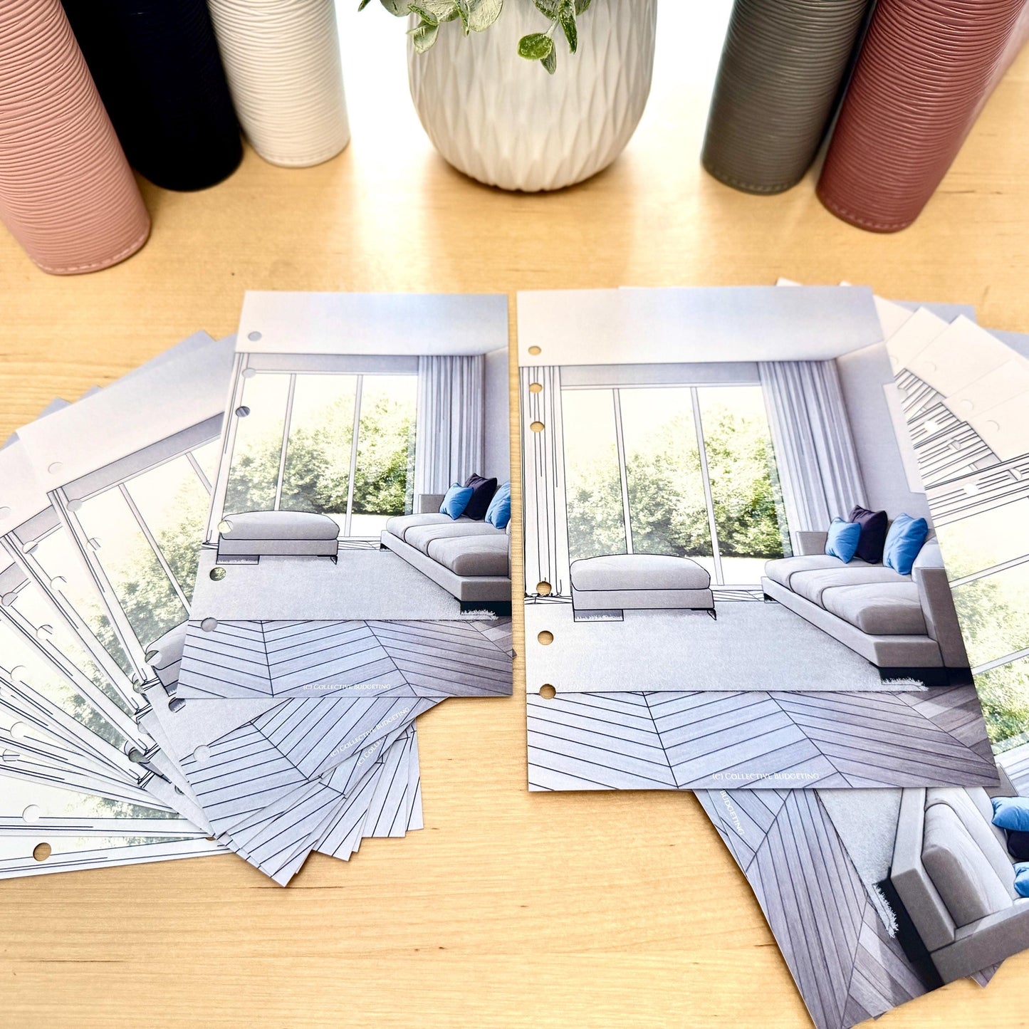 Two sets of printed pages with a design of a living room with a couch, two chairs, and a large window. The pages are designed to be used in a planner or journal.
