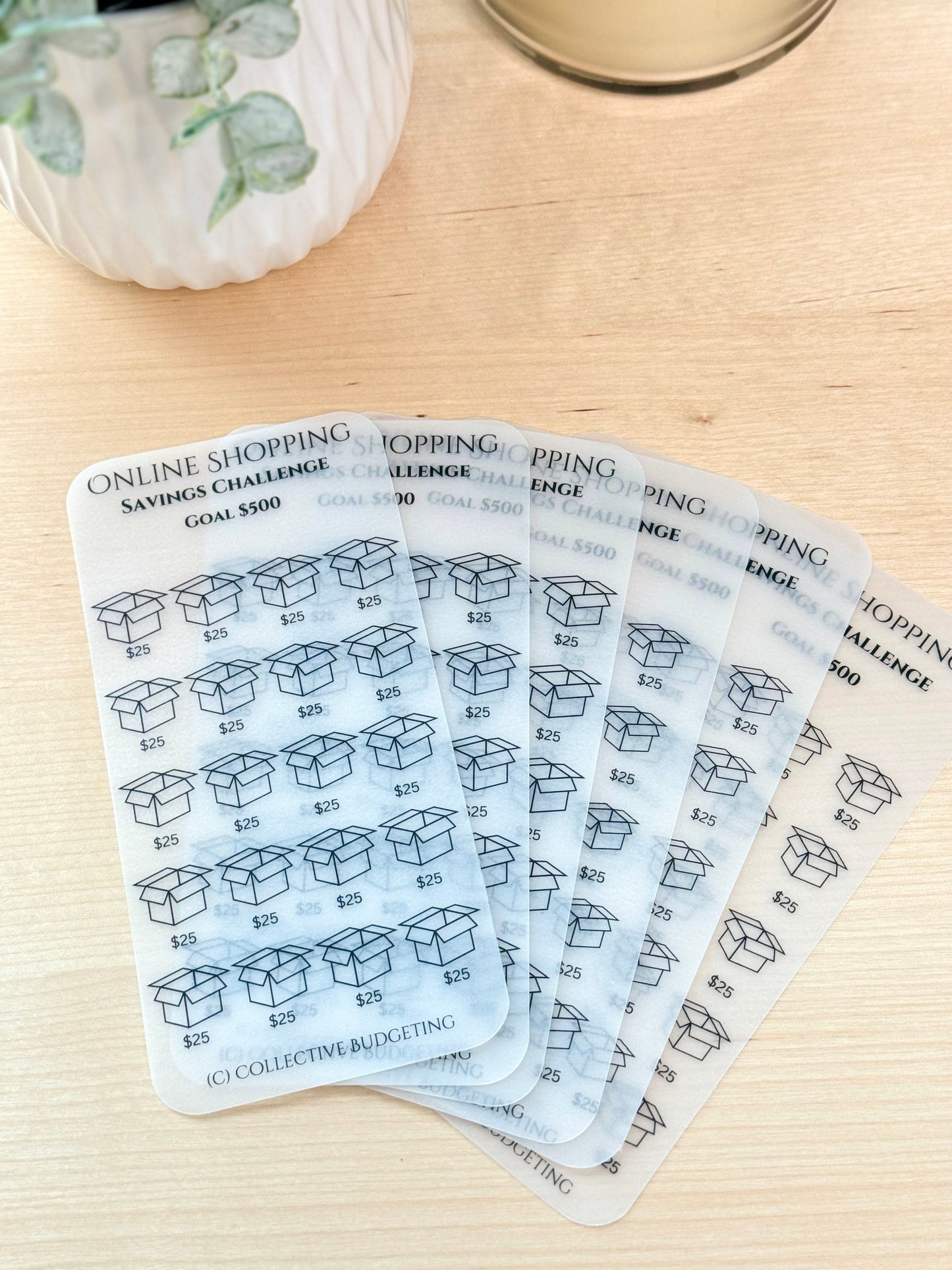 A set of seven transparent sheets with a black and white design. Each sheet has a title that reads 'Online Shopping Savings Challenge Goal $500' and features a grid of 25 boxes with the number $25 written inside each box. The bottom of each sheet has the text '(C) Collective Budgeting'.